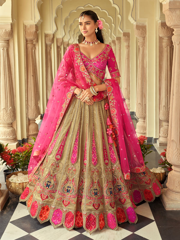 Woman in a traditional pink and beige embroidered outfit standing in an ornate architectural setting.