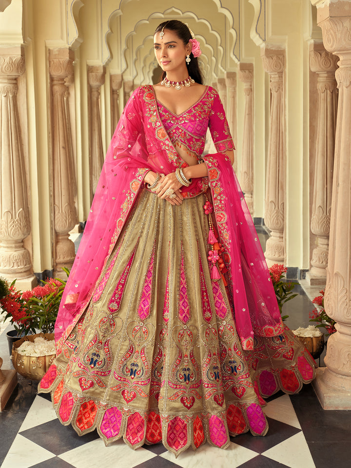 Woman in a traditional pink and beige embroidered outfit standing in an ornate architectural setting.