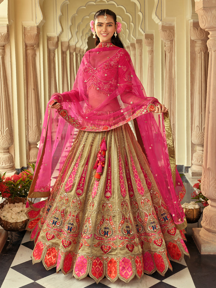 Woman in traditional pink and gold embroidered outfit with floral decorations in a decorative setting.