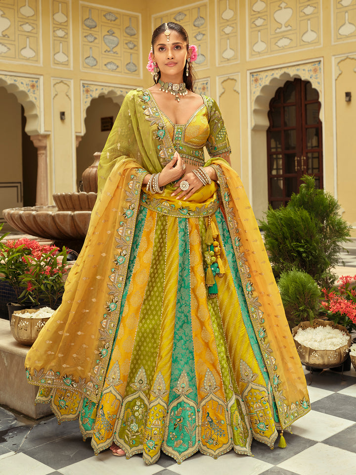 Woman in a traditional yellow and green outfit standing in an ornate indoor setting.