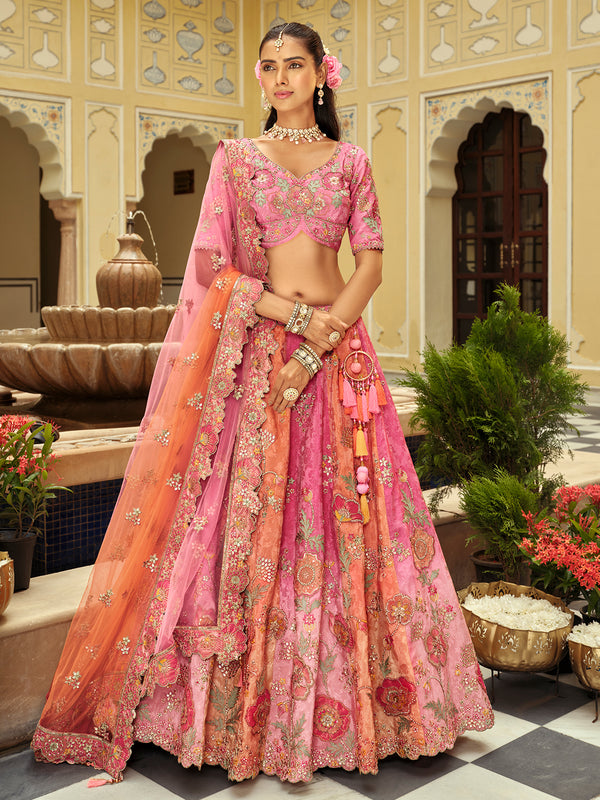 Woman in a traditional pink and orange embroidered outfit standing in an ornate courtyard.