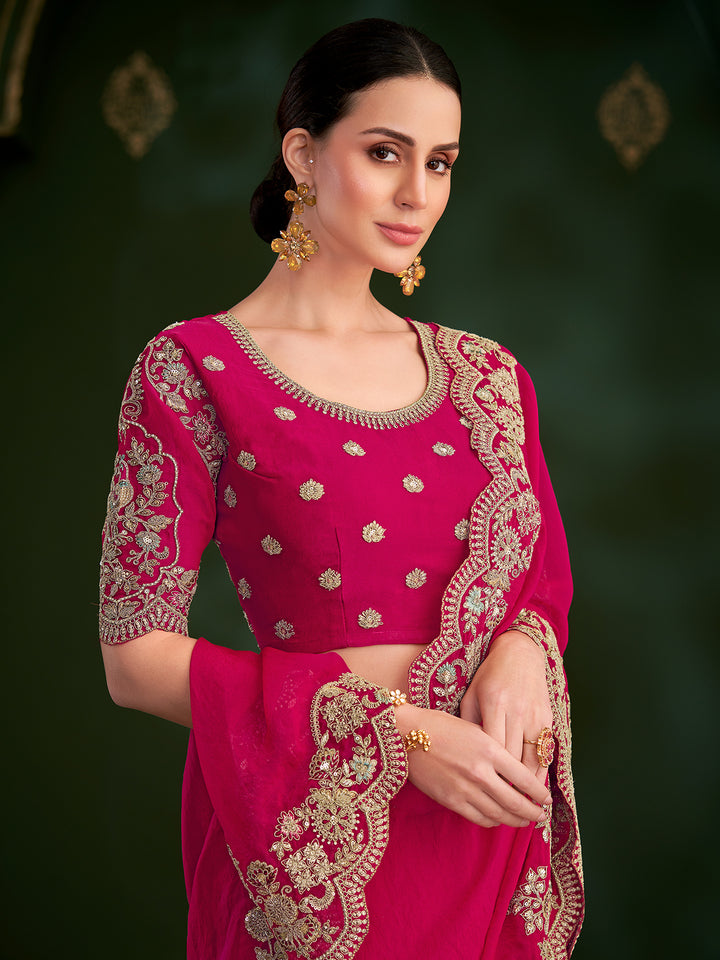 Woman wearing a pink traditional outfit with gold embroidery on a dark background