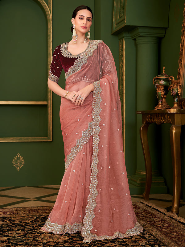 Woman wearing a pink saree with silver border in an elegant room.