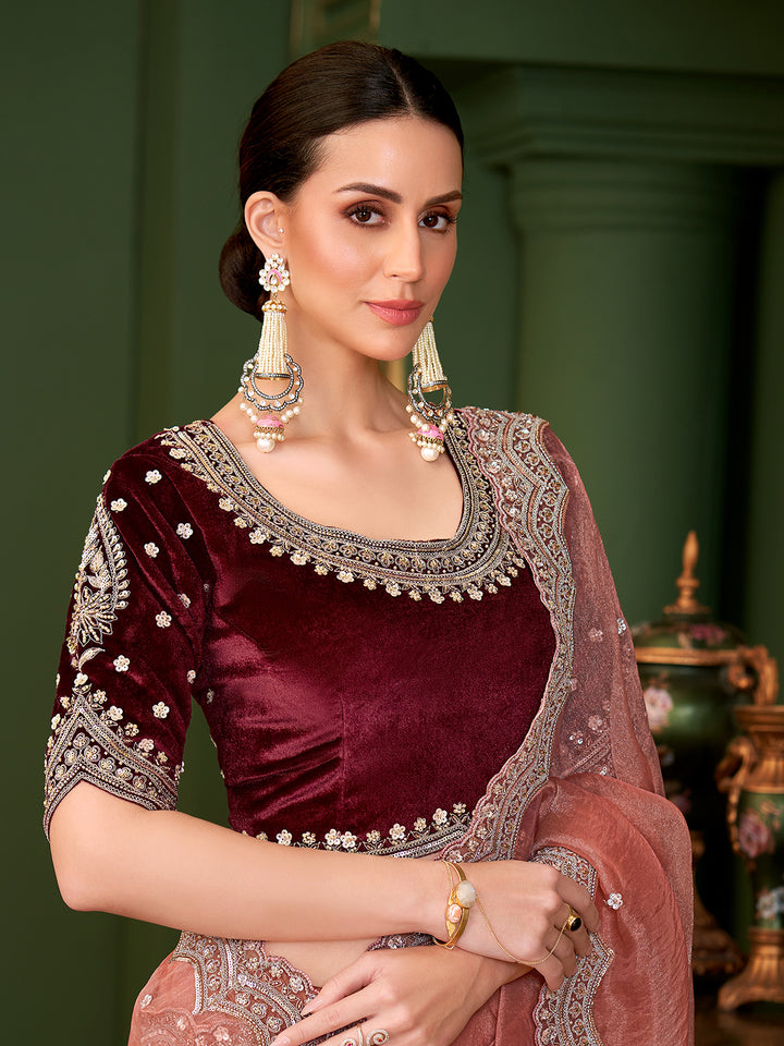 Woman wearing a maroon saree with intricate silver embroidery against a green background