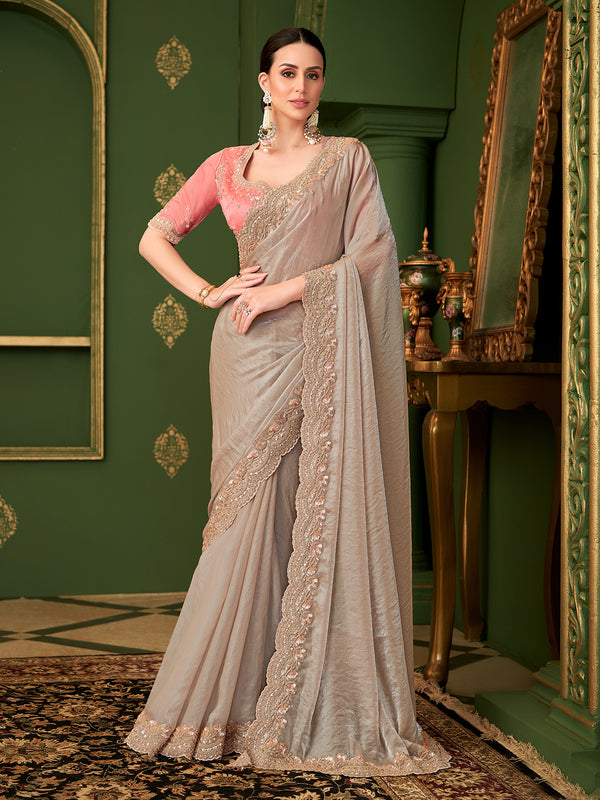 Woman in a gray saree with gold embroidery in a decorated room.