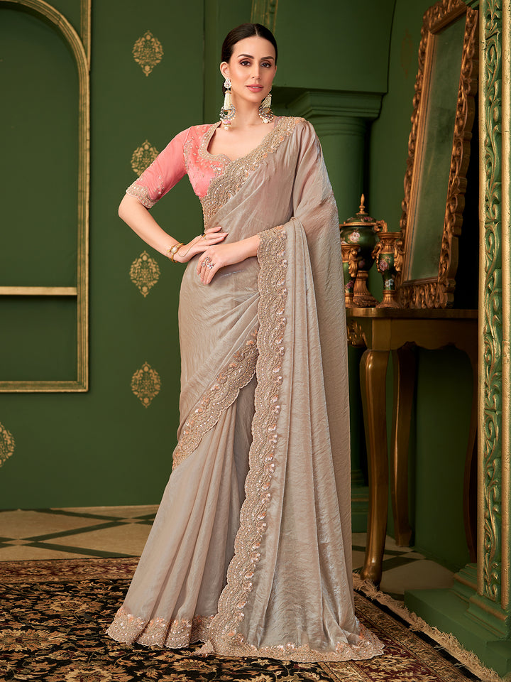 Woman in a gray saree with gold embroidery in a decorated room.