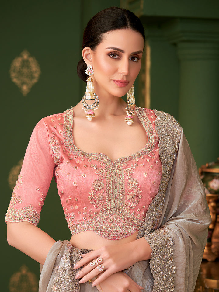 Woman wearing a pink embroidered blouse with a gray dupatta against a green background