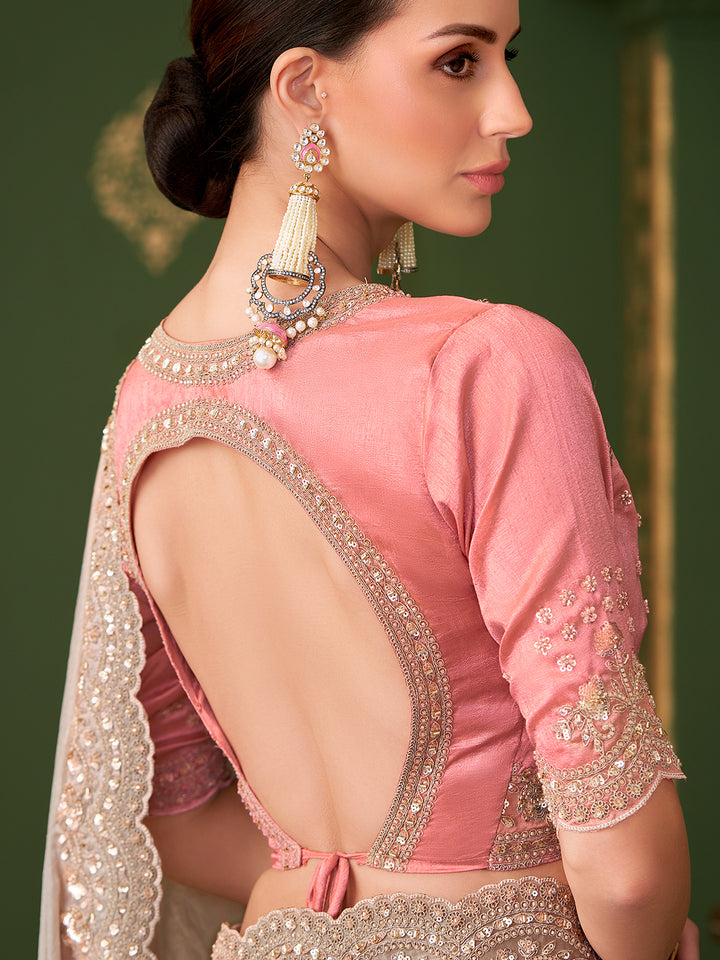 Woman wearing a pink blouse with intricate designs and embellishments.