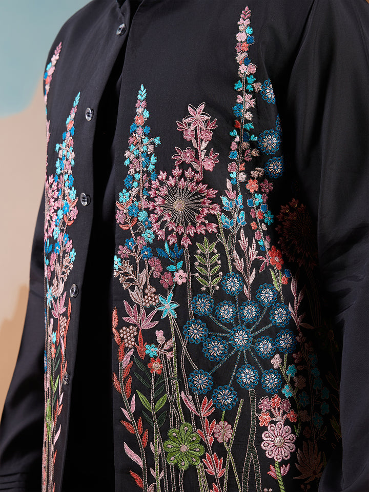 Black embroidered garment with colorful floral patterns on a neutral background