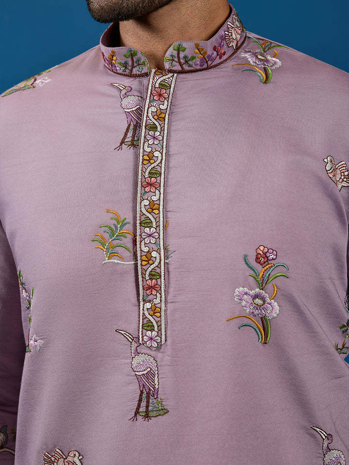 Close-up of a lavender embroidered shirt with floral and bird patterns on a blue background