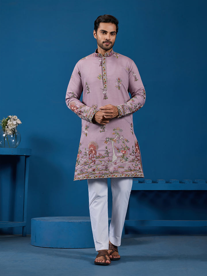 Man wearing a pink embroidered kurta with white pants against a blue background