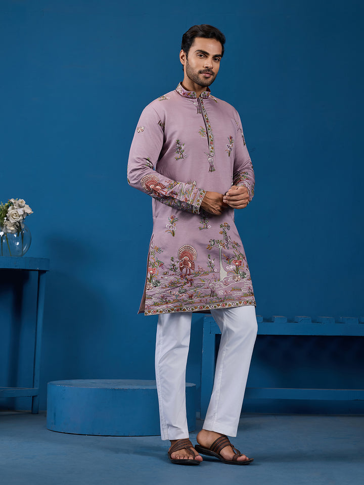Man wearing a pink embroidered kurta with white pants against a blue background