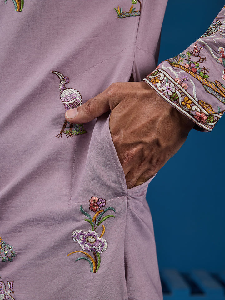 Close-up of a lavender garment with floral embroidery on a blue background