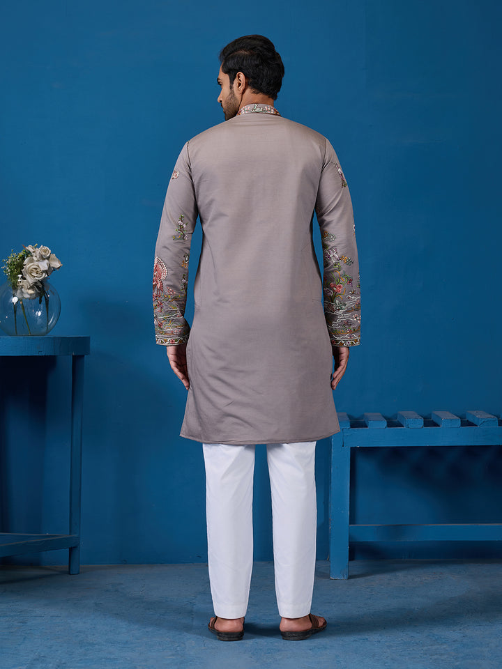 Man wearing a gray kurta with white pants against a blue background